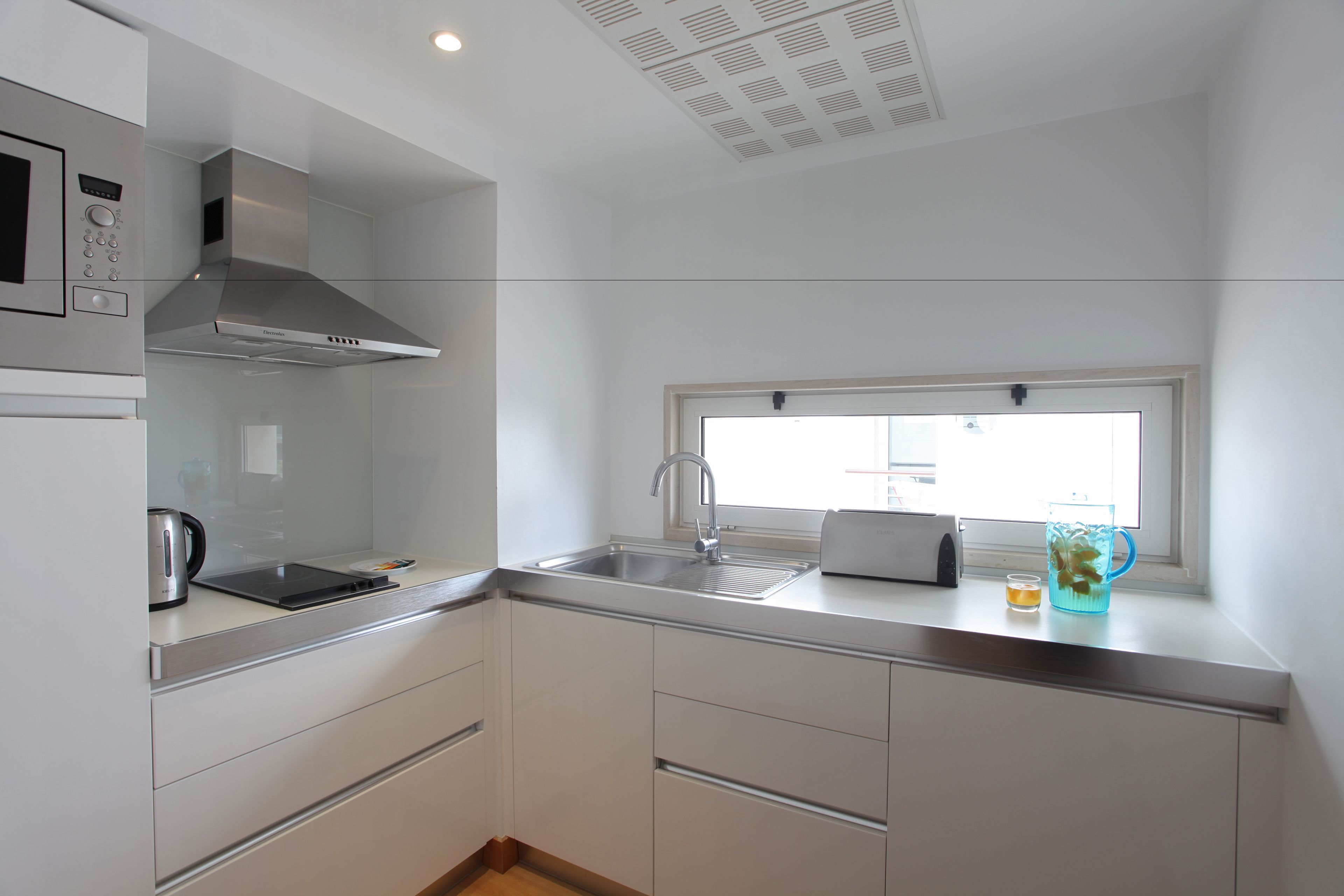 Una cocina moderna con microondas, tostadora y pileta.