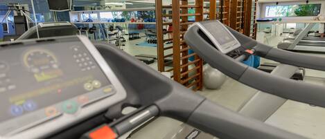A gym with treadmills, exercise equipment, and a television screen.