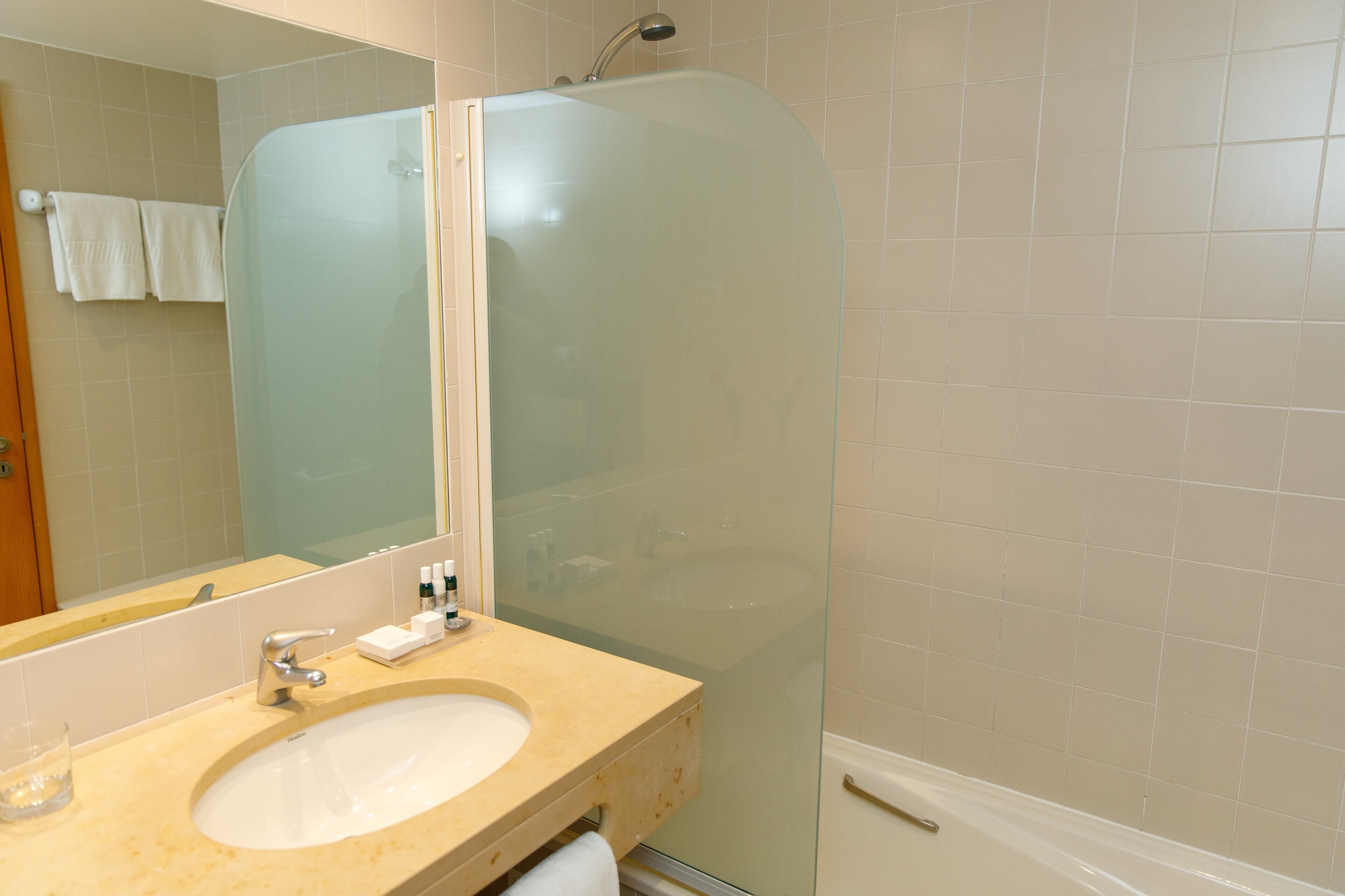 Une salle de bain avec une douche à parois de verre, un lavabo et un miroir.