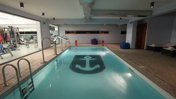 An indoor swimming pool with a central anchor design, surrounded by exercise equipment and seating areas.