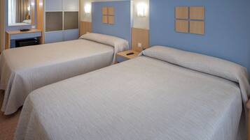Habitación de hotel con dos camas, un escritorio, un espejo y luces en la pared.