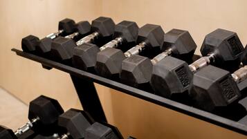 A rack of black hexagonal dumbbells with weight markings, arranged on a black stand.