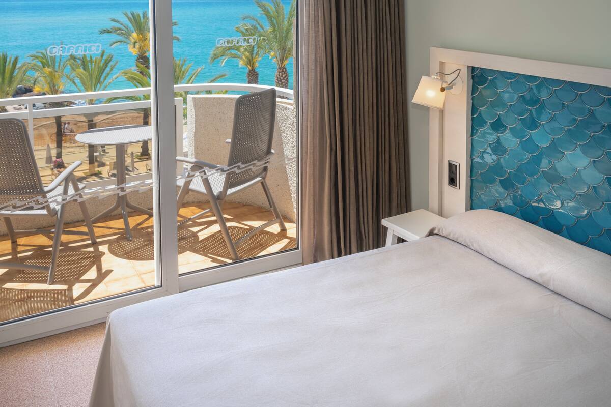 Een hotelkamer met balkon, een bed en uitzicht op de oceaan.
