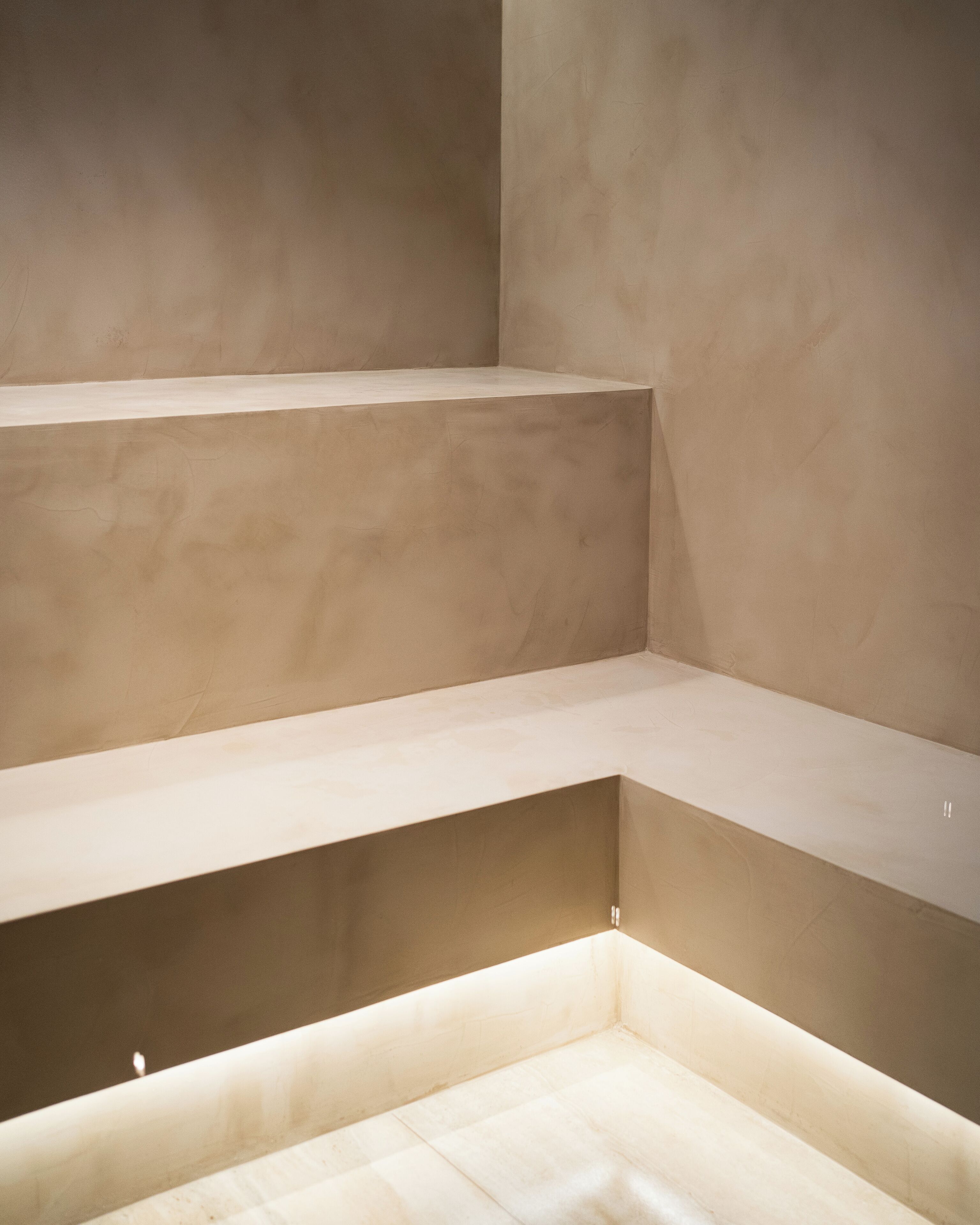 Um interior minimalista com três prateleiras fixadas em uma parede lisa.