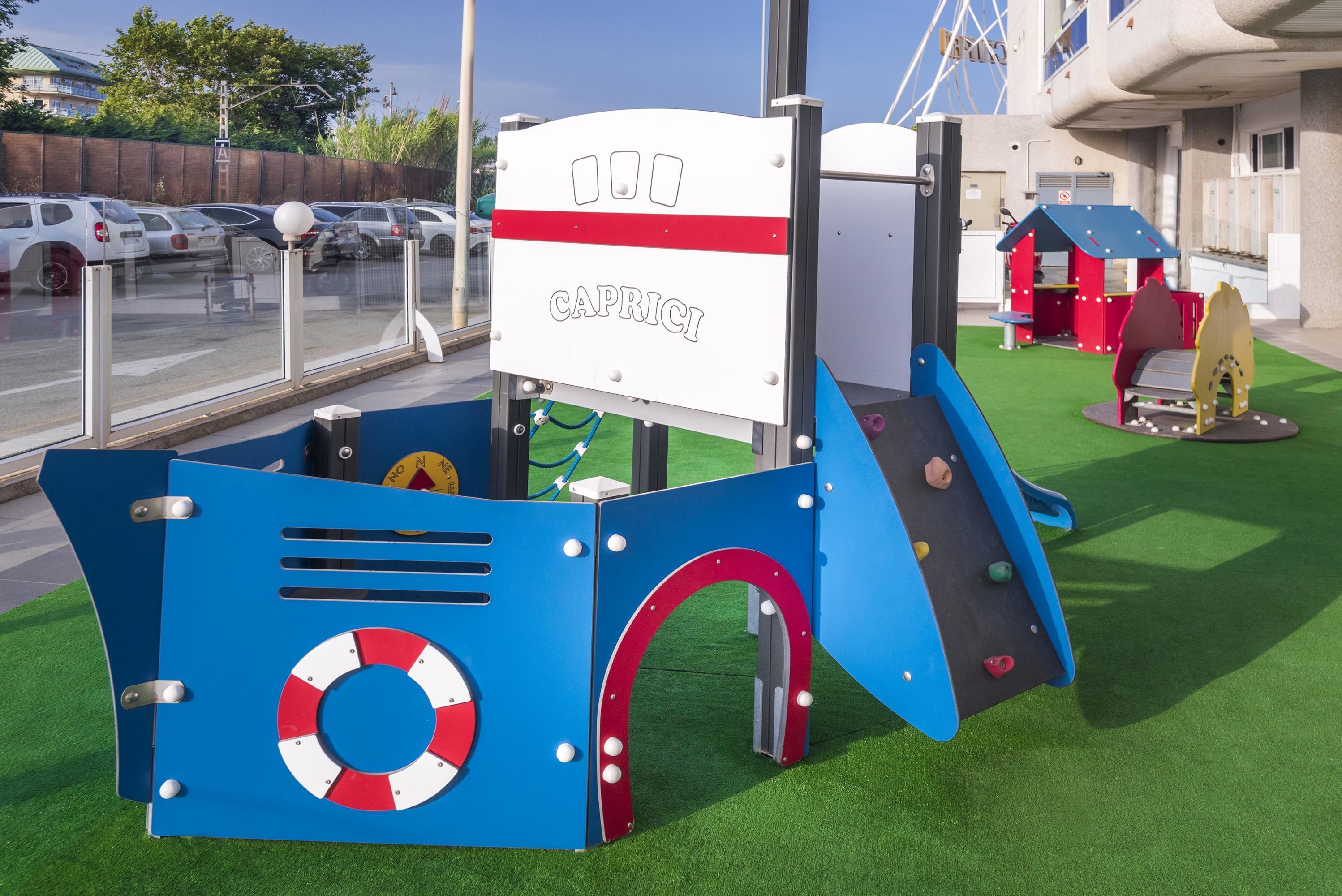 A children's play area with a slide, climbing wall, and a sign that reads "CAPRICCI".