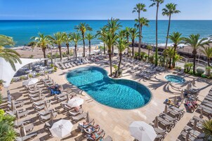 Una piscina al aire libre, sombrillas, sillones reclinables de piscina