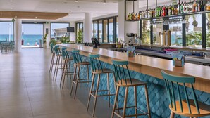 Un espace bar doté d’un long comptoir, de nombreux tabourets et offrant une vue sur l’océan.