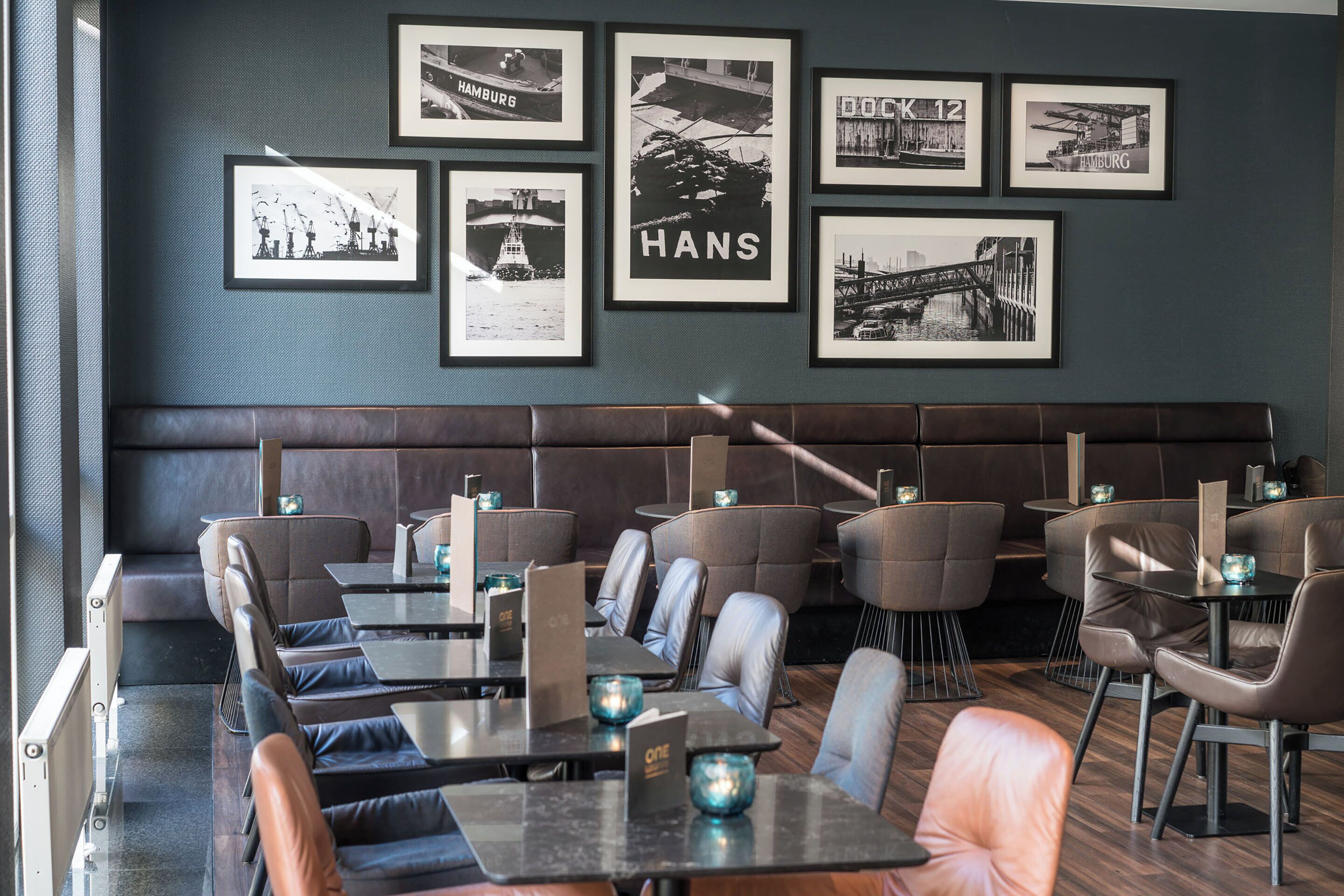 A restaurant with booths and tables, framed pictures on the wall, and a dark color scheme.