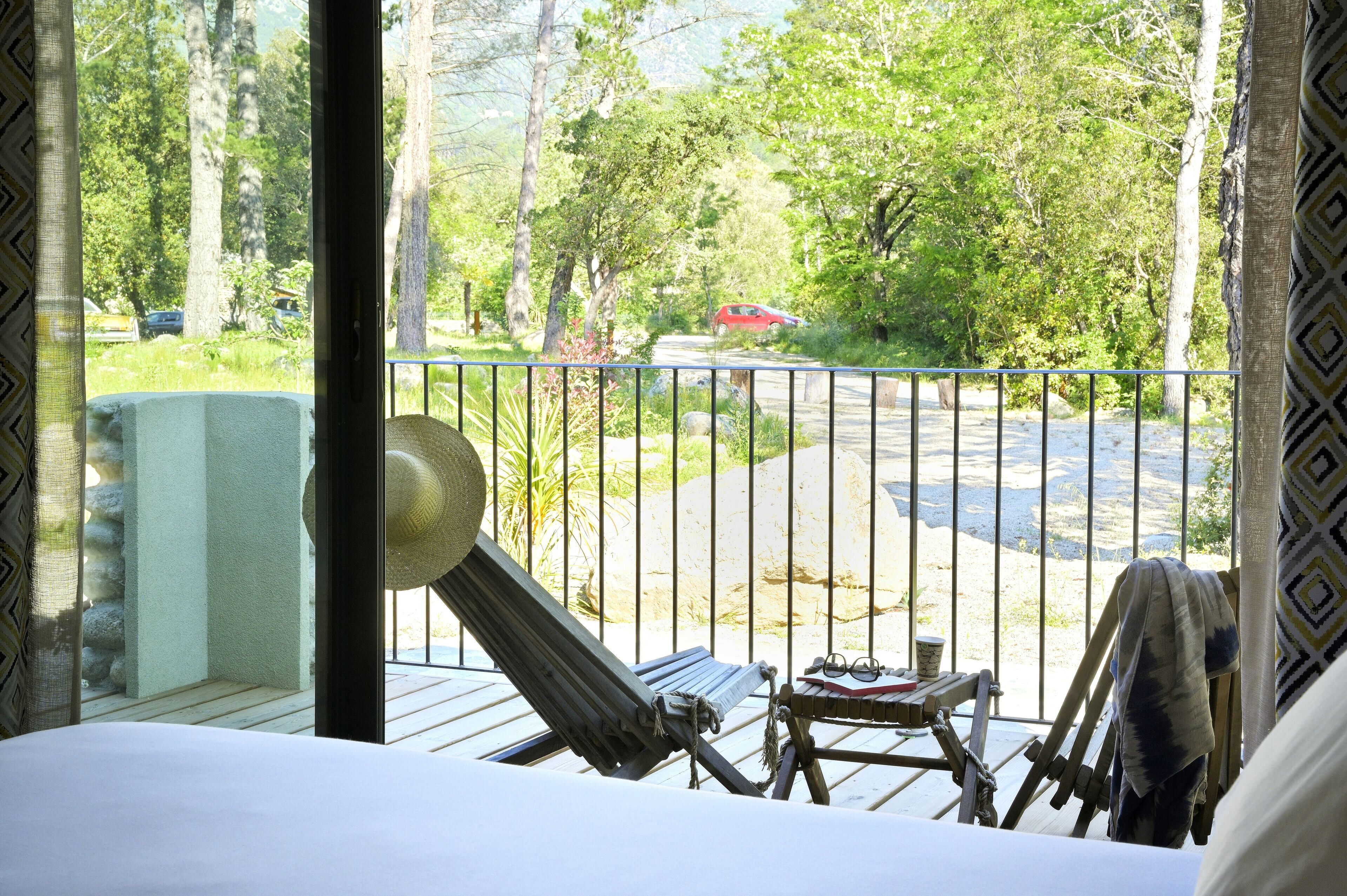 A balcony with a view of a parking area and trees.