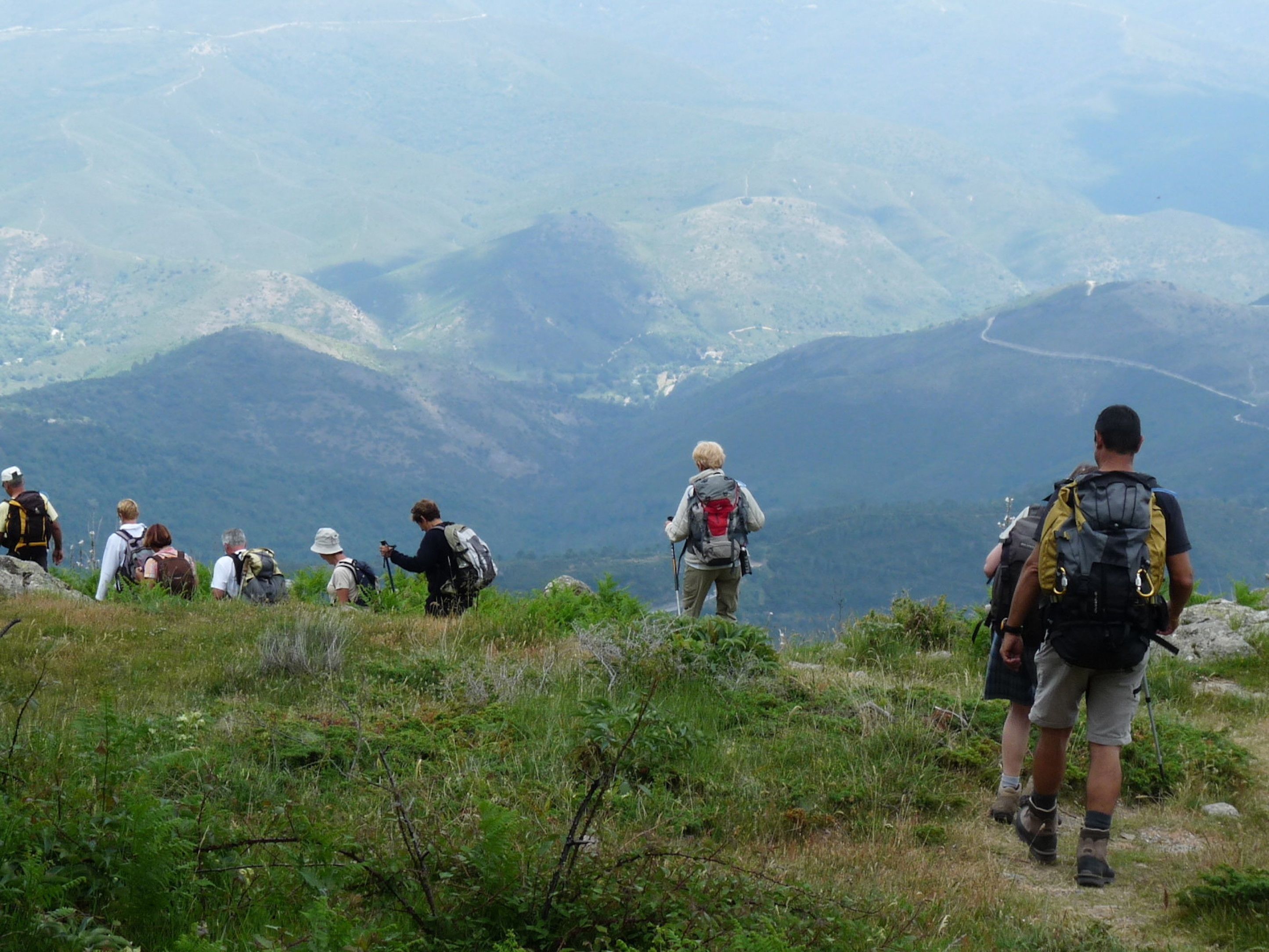 Een groep wandelaars op een bergpad met uitzicht op verre bergen.