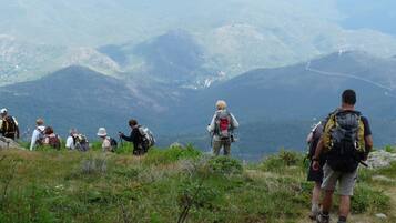Een groep wandelaars op een bergpad met uitzicht op verre bergen.