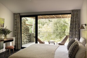 A bedroom with a large bed, a desk with a chair, a small table, and a hammock.