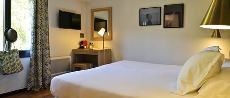 Un dormitorio ordenado con cama, mesita de noche, lámpara y ventana con cortinas.