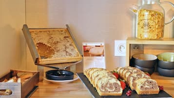 Mostrador de panadería con pan, pasteles, una cafetera y un letrero con recetas.
