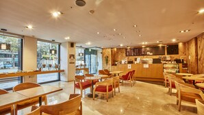 A modern coffee shop interior with wooden furniture, a counter with a menu, and a view of the street outside. - Provista Hotel (Seoul)
