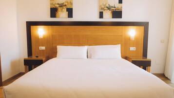 Una habitación de hotel con una cama grande, dos mesitas de noche y dos lámparas de pared.