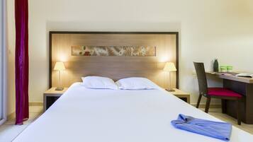 Une chambre d’hôtel avec un grand lit, deux lampes de chevet, un bureau avec une chaise et une tête de lit décorative.