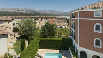 Un quartier résidentiel doté d’une piscine, de pelouses verdoyantes et d’immeubles aux toits couverts de tuiles.