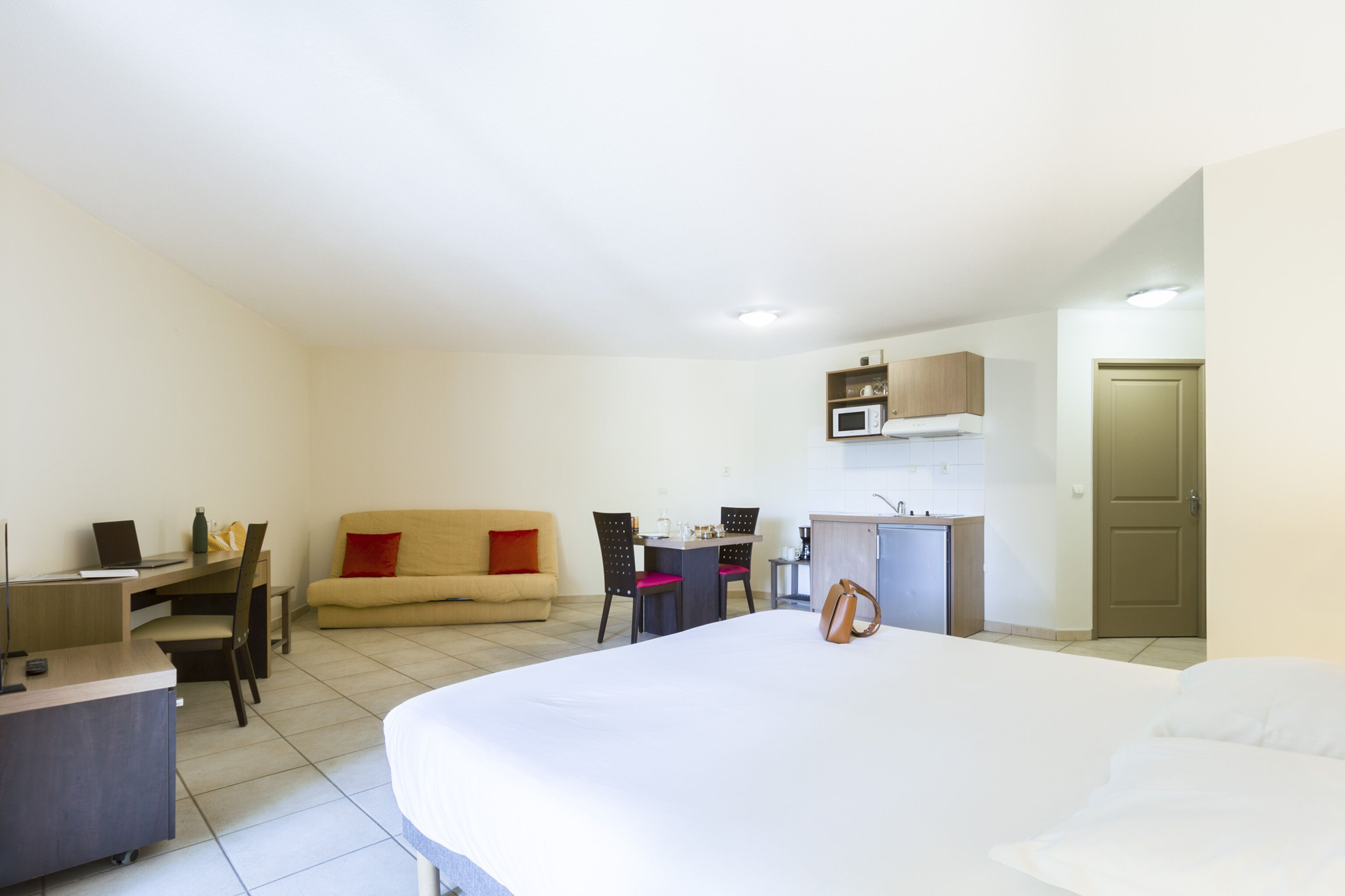 Una camera d'albergo con un letto, una scrivania, un divano, un tavolo da pranzo e angolo cottura.
