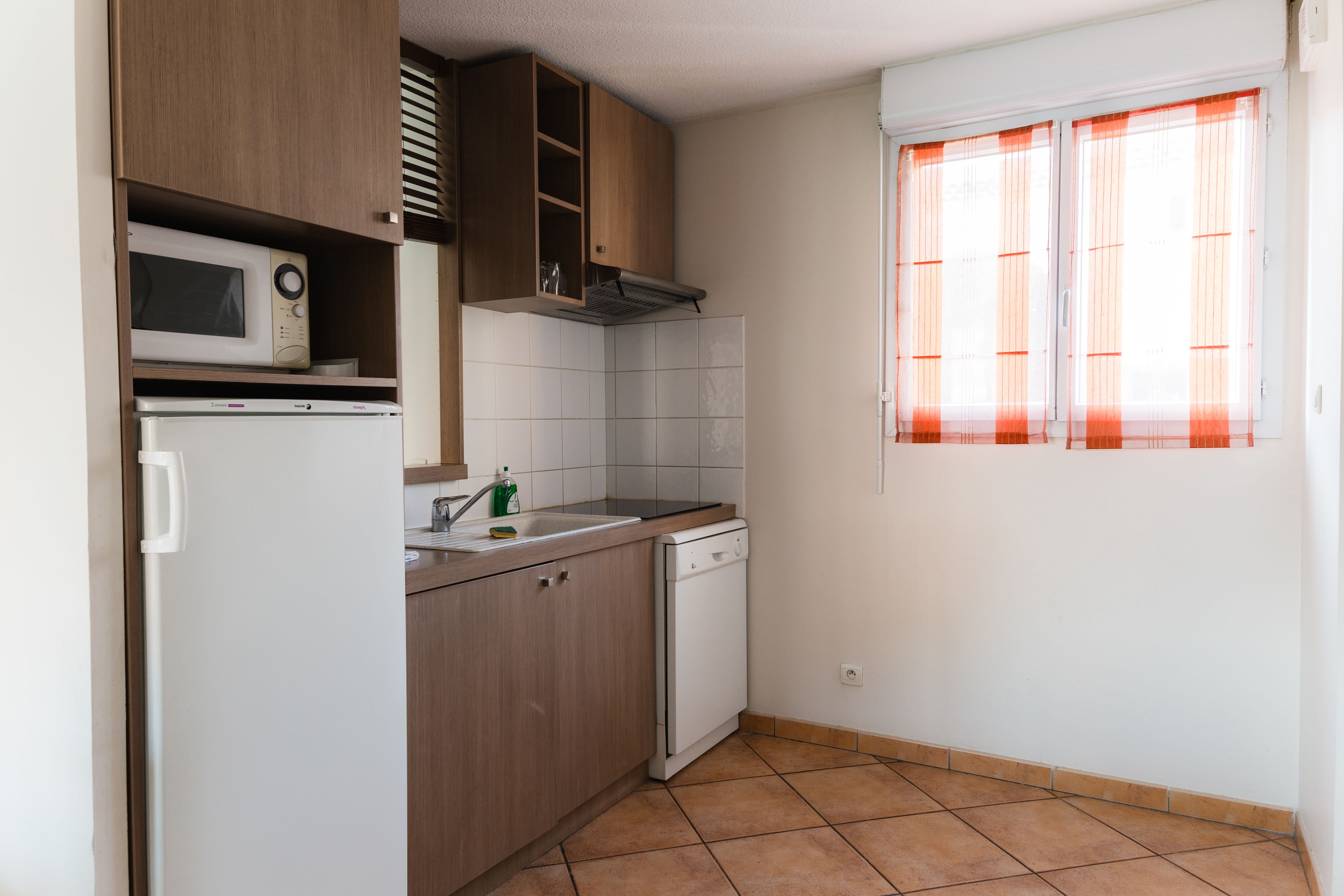 Una cocina compacta equipada con microondas, horno integrado, pileta y lavavajillas.