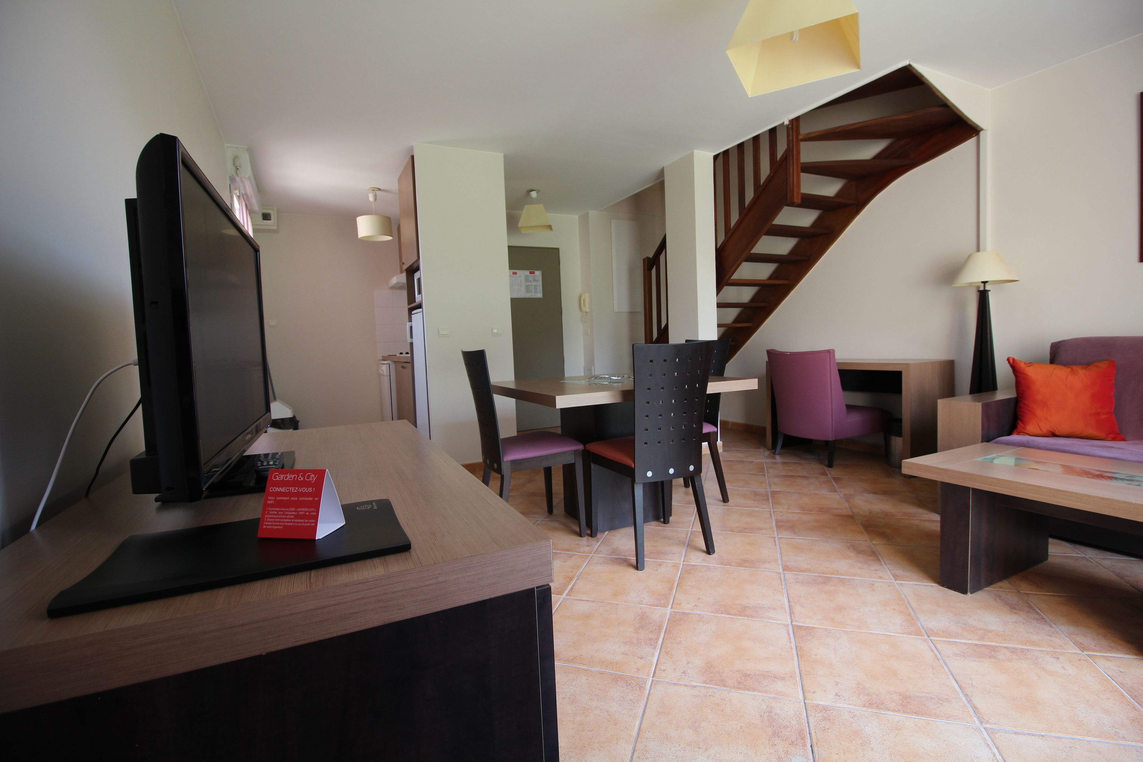 Ein Hotelzimmer mit Schreibtisch, Computer und einem Essbereich mit Stühlen und Tisch.