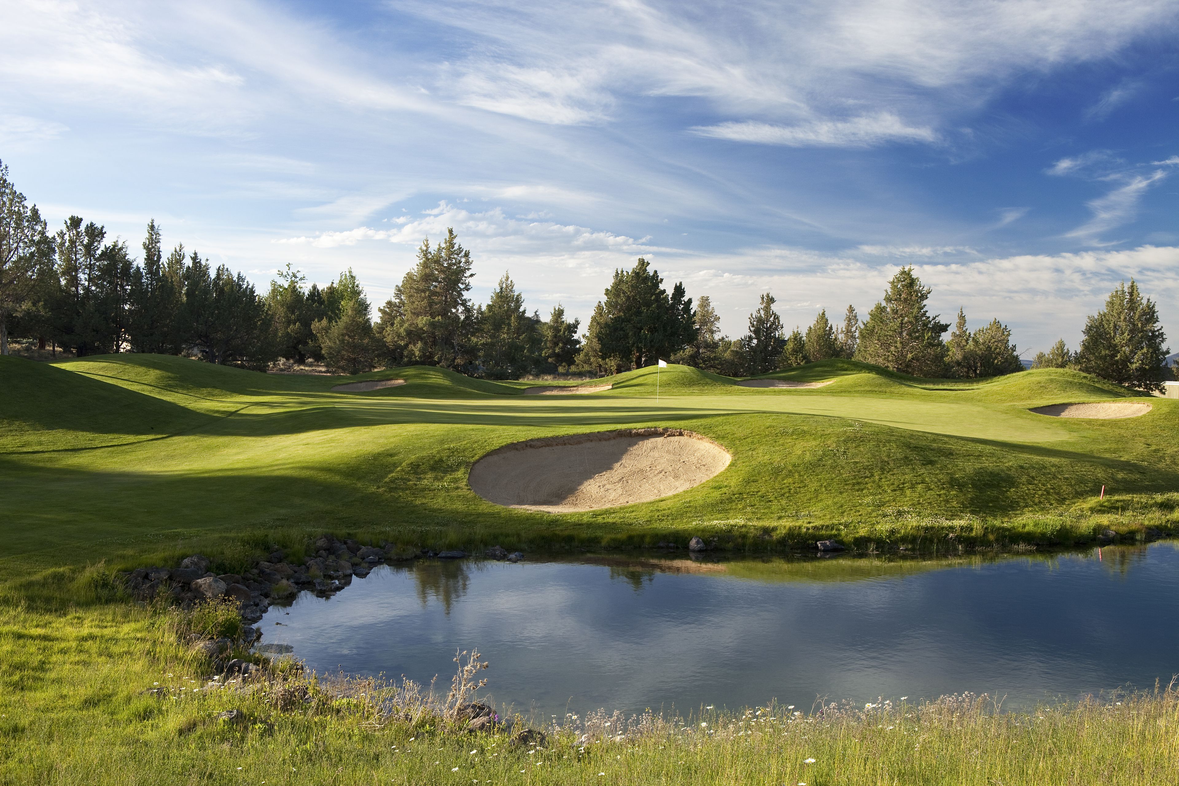 A golf course with a pond, sand bunkers, and trees.