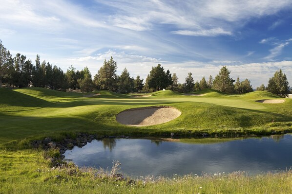 A golf course with a pond, sand bunkers, and trees.