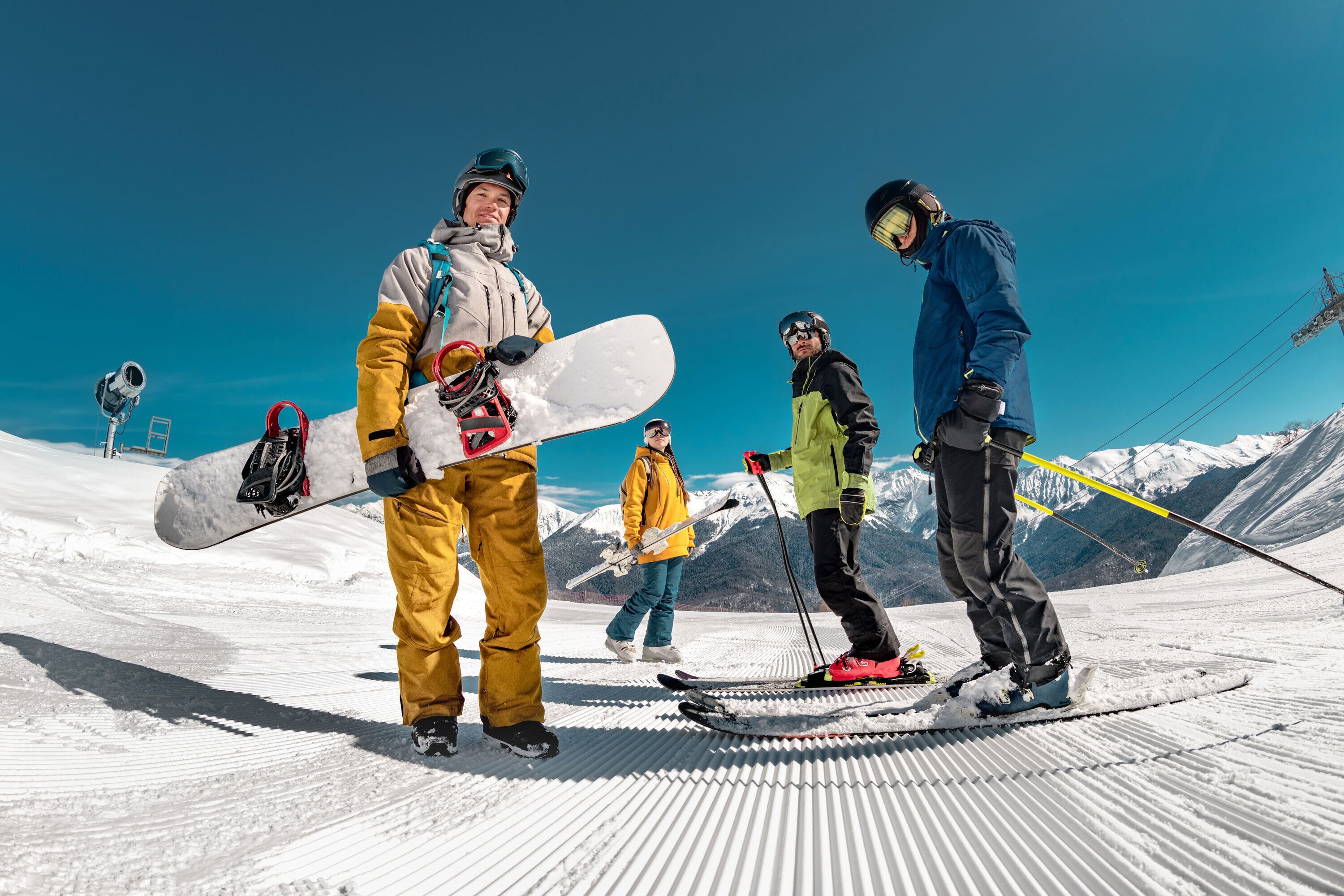 Un groupe de skieurs sur une pente enneigée, avec des montagnes en arrière-plan.