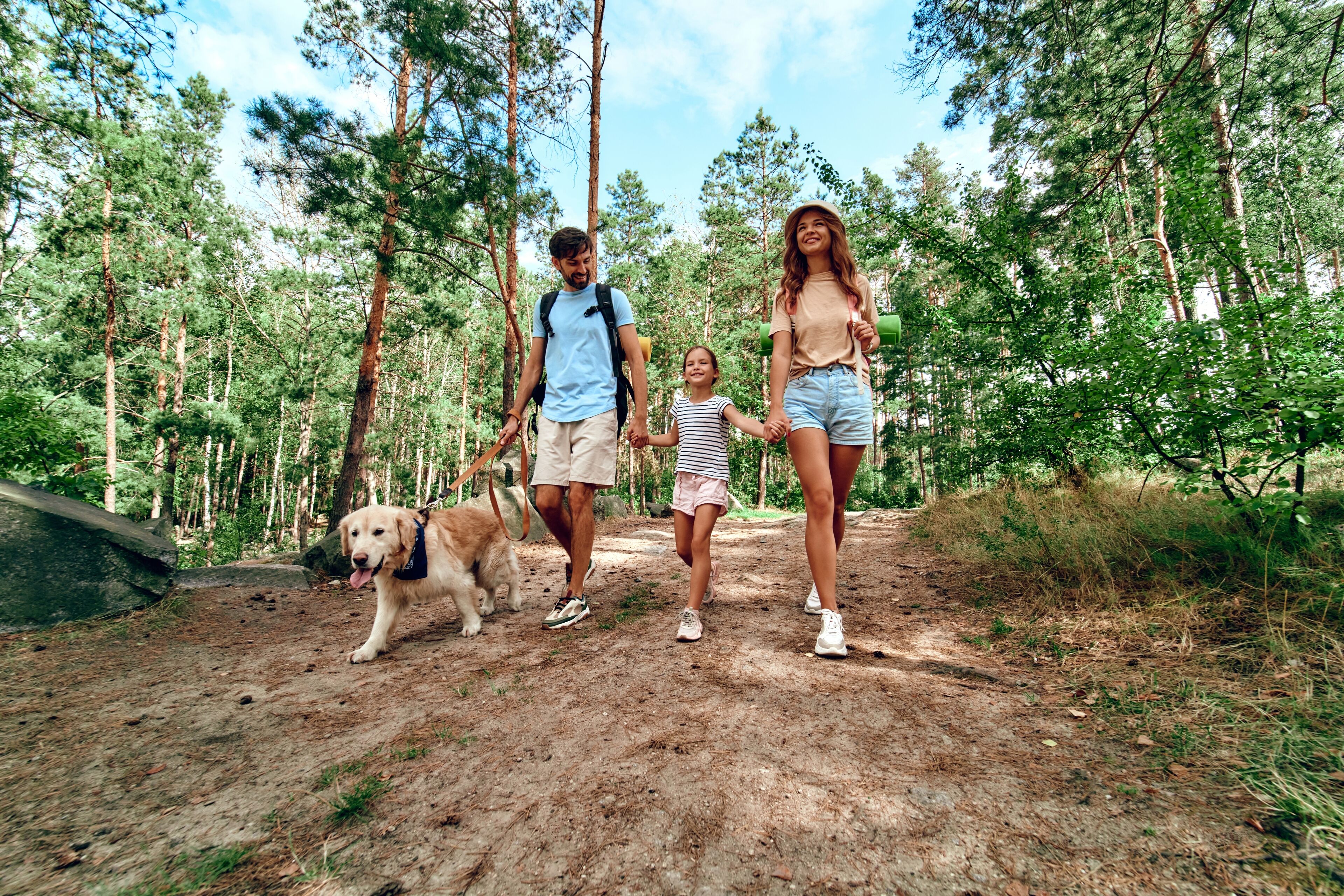 A family walking on a dirt path in a forested area.