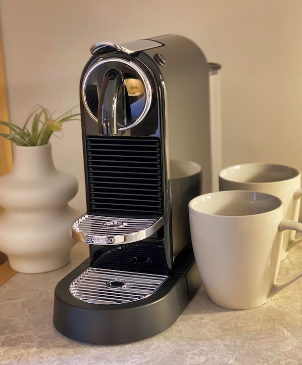 Máquina de café com design elegante, reservatório de água e bandeja coletora de gotas.