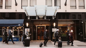 L’entrée d’un hôtel, avec un auvent en verre, une enseigne indiquant «AURA HOTEL» et une décoration de Noël.