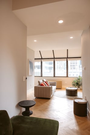 A modern living room with a sofa, a round coffee table, and a green armchair.