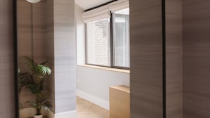 Un intérieur moderne avec un parquet en chevrons, une plante en pot, une fenêtre avec des stores et un luminaire.