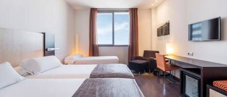 A hotel room with two beds, a desk, a chair, a television, and a window with curtains.