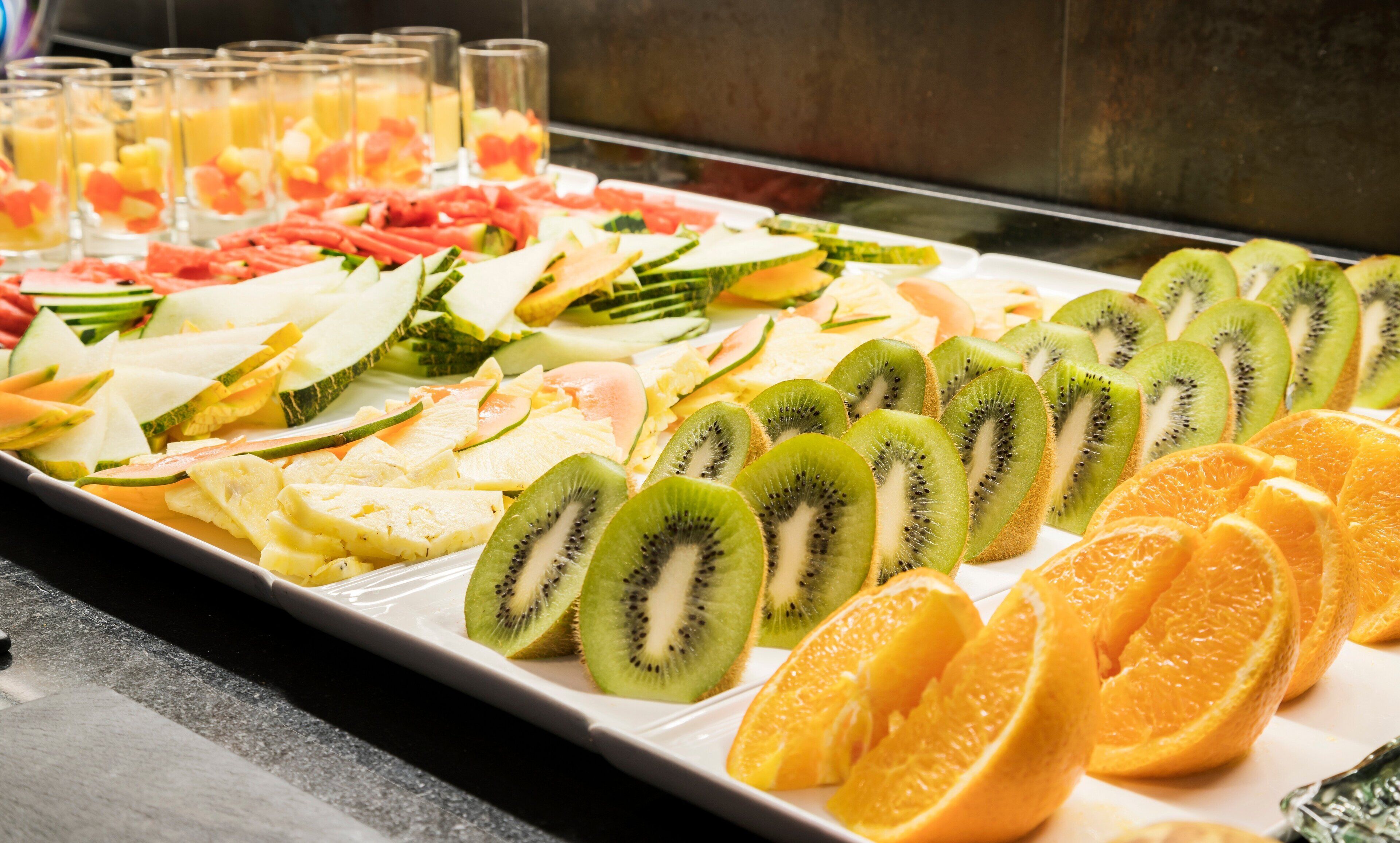 A buffet with various fruits and juices.