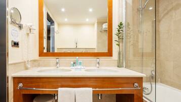 Une salle de bain avec un meuble-lavabo à deux vasques, un grand miroir, une douche à parois de verre et un porte-serviettes.