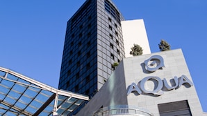 Un edificio moderno con fachada de vidrio y un llamativo letrero 'AQUA' en la parte lateral.
