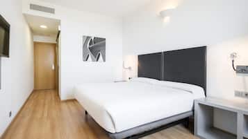 Een moderne hotelkamer met een groot bed, een nachtkastje, een tv aan de wand en een houten vloer.