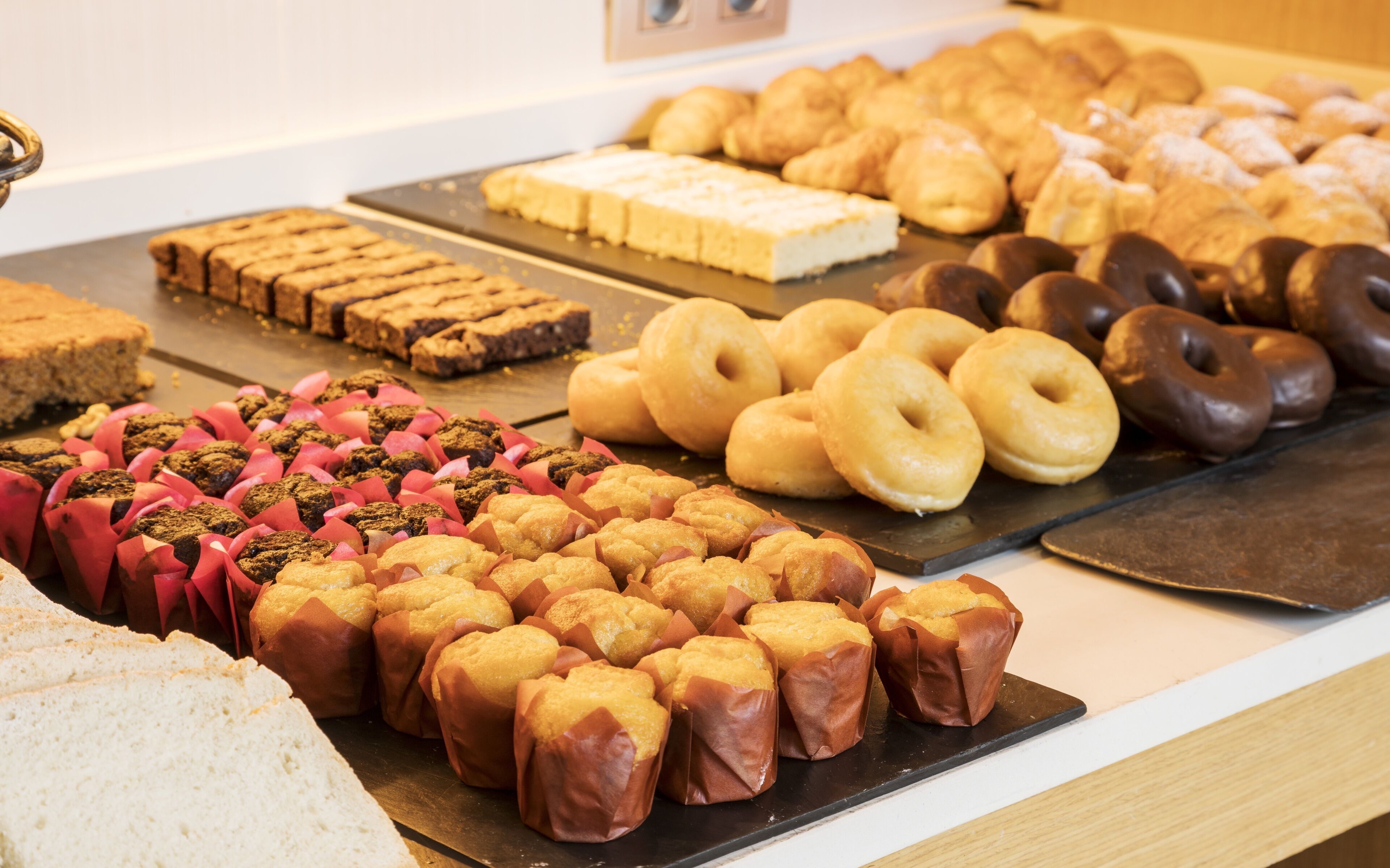 Une variété de produits de boulangerie, notamment des muffins, des beignets et des pâtisseries, présentés sur un comptoir.