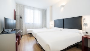 A hotel room with two beds, a TV, a desk, and a window with curtains. - Hotel ILUNION Aqua 3 (Valencia)