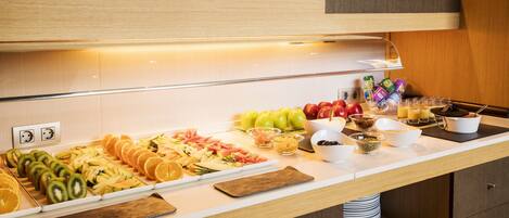 A buffet with various fruits, vegetables, and prepared foods.
