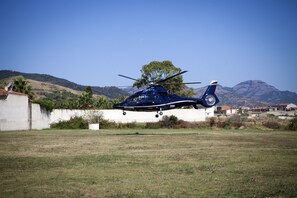Un helicóptero sobre un campo cubierto de hierba con montañas al fondo.
