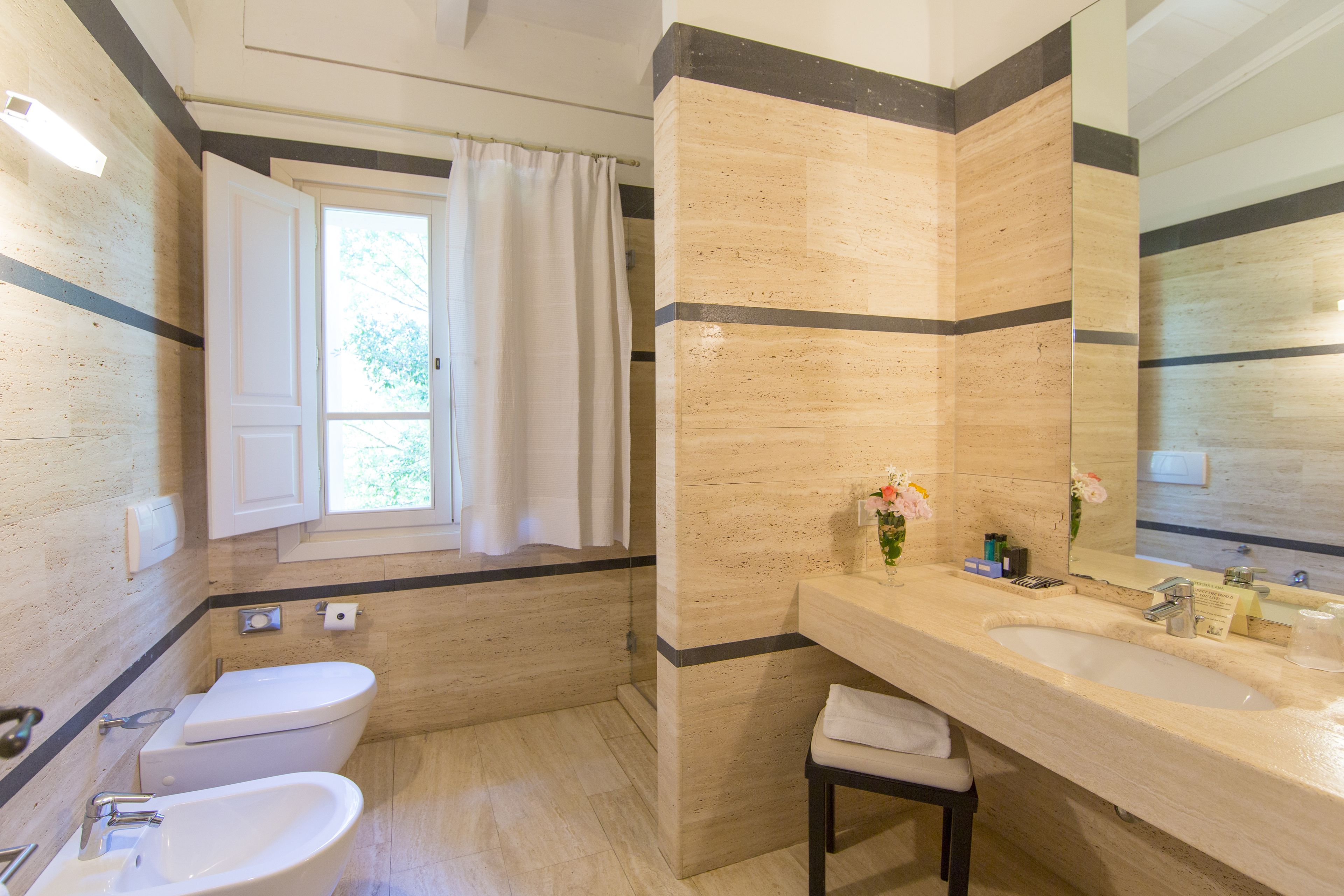Ein Badezimmer mit Toilette, Bidet, Waschbecken und einem großen Spiegel.