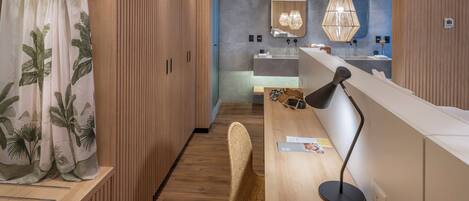 A modern bathroom with wooden cabinetry, a large mirror, and a stylish pendant light.