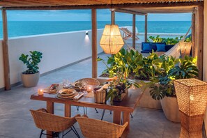 A wooden table set for dining with potted plants, wicker chairs, and a hanging light fixture. - Serhs Natal Grand Hotel & Resort (Natal)