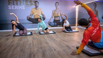 A fitness class in a studio with wooden flooring and a wall with motivational posters.