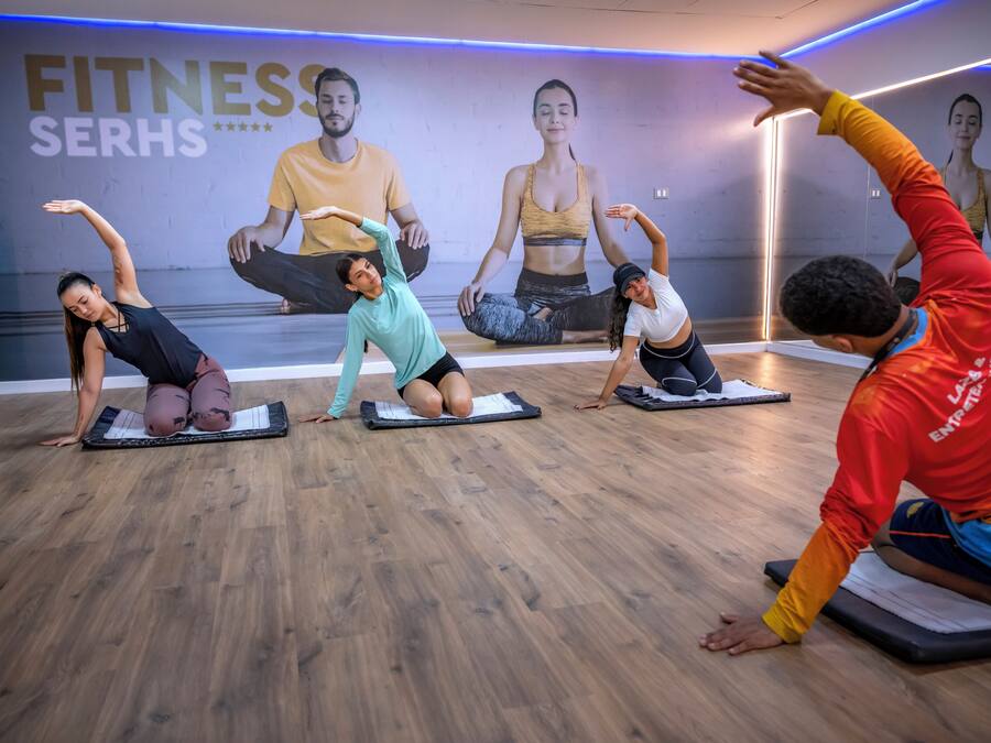 A fitness class in a studio with wooden flooring and a wall with motivational posters.