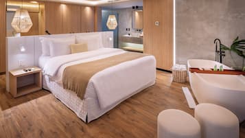 Un dormitorio moderno con una cama grande, mesitas de noche, un tocador con espejo y una bañera.