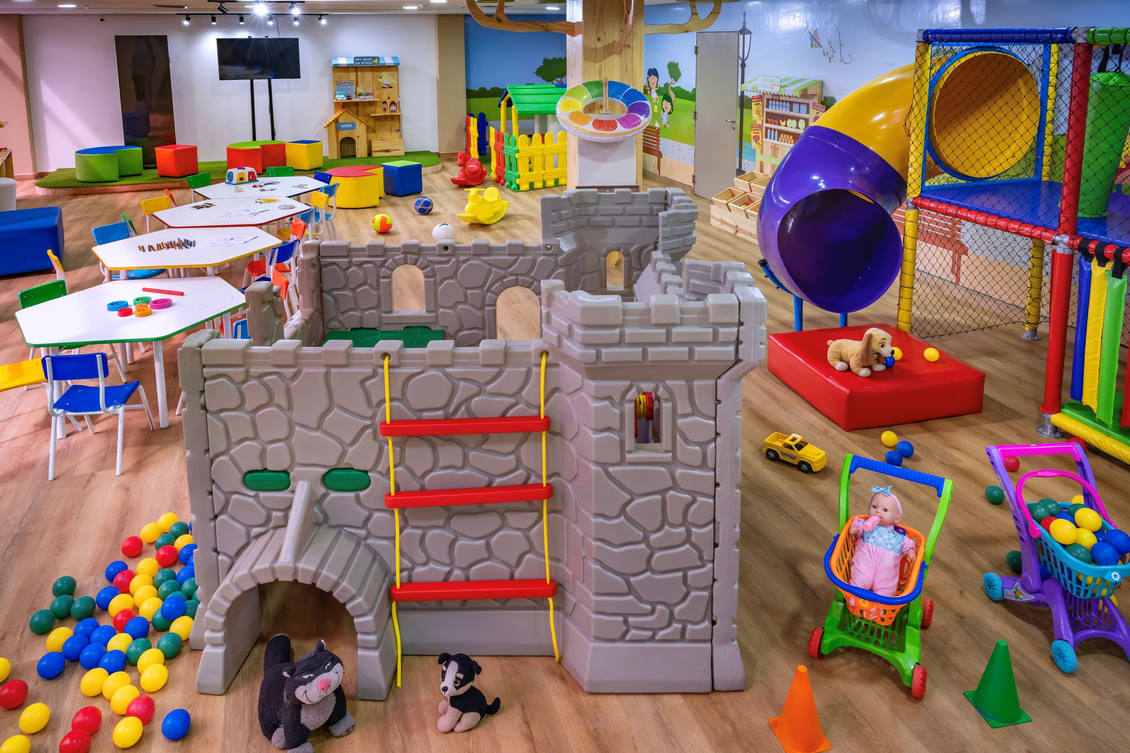 Ein Spielbereich für Kinder mit einer Burg-Spielkonstruktion, einer Rutsche und verschiedenen Spielsachen.