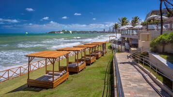 Um hotel à beira-mar com áreas de estar ao ar livre, um caminho para a praia e vista para o oceano e o horizonte da cidade.